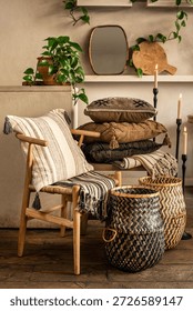 A comprehensive interior styling scene featuring a light wood Wishbone chair with a striped cushion, a stack of boho pillows on a wooden bench, and green geometric woven baskets. The warm atmosphere i