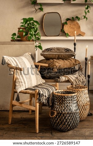 A comprehensive interior styling scene featuring a light wood Wishbone chair with a striped cushion, a stack of boho pillows on a wooden bench, and green geometric woven baskets. The warm atmosphere i