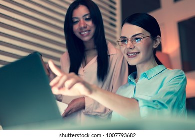 Comprehensive Report. Beautiful Young Woman Pointing At The Laptop Screen And Telling Her Female Boss About The Current Work Progress