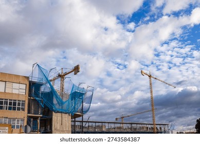 A comprehensive view of the construction site for the new wings of the Villajoyosa Hospital, highlighting multiple yellow cranes and the structural framework of the rising medical facility.