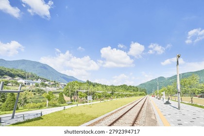        A comprehensive visual collection showcasing the contrasting day and night views of Najeon Station, a tranquil rural railway station in Jeongseon, South Korea. The daytime images feature a sunlit platform with a classic white station signboard, straight railway tracks, and lush green mountains under a bright blue sky with fluffy white clouds. The nighttime image captures the quaint station building with a red roof illuminated against a dark, starry sky with dramatic long-exposure clouds. This series beautifully captures the serene passage of time in a quiet countryside landscape.                       