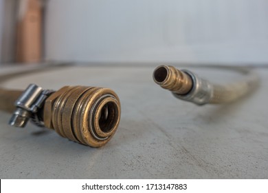 A Compressed Air Hose With Coupling Is Lying On The Floor Of A Workshop