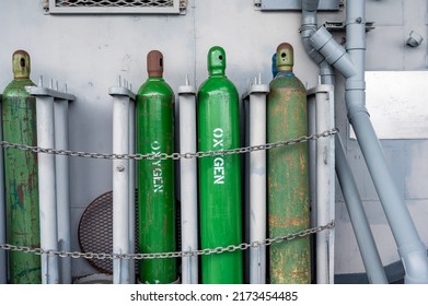 Compressed gas cylinders being stored vertically secured by a metal chain and a metal cap. - Shutterstock ID 2173454485