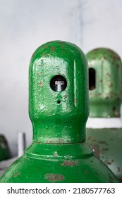 Compressed Gas Cylinders Being Stored Vertically Secured By A Metal Chain And A Metal Cap.