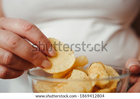 Compulsive overeating, mindless snacking, junk food, unhealthy meals. Woman eating chips from bowl, close up