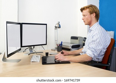 Computer Aided Design (CAD) Engineer At Work Behind Two Large Monotors, Using A Tablet And Graphic Pen In Product Development