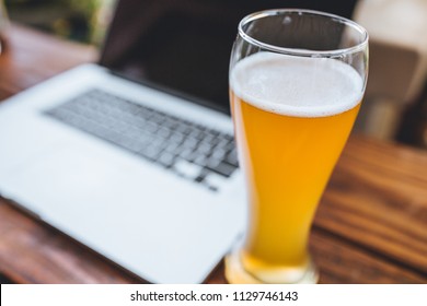 Computer and beer on a wooden desk or table. modern workflow while outdoors. working on tech.  - Powered by Shutterstock