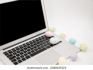 Computer with blank empty screen on white background of easter eggs. Space for text. Happy Easter! 