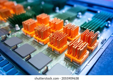 Computer board with orange heatsinks. PCB heat sinks are equipped with heat sinks. Individual heatsinks on computer board. Multicolored PCB close up. Microprocessor-based heat dissipation devices