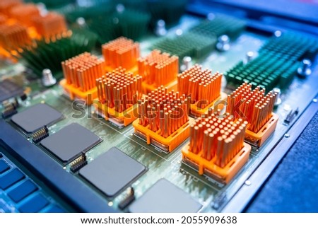 Computer board with orange heatsinks. PCB heat sinks are equipped with heat sinks. Individual heatsinks on computer board. Multicolored PCB close up. Microprocessor-based heat dissipation devices