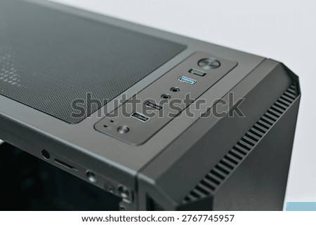 A computer case sits on a flat surface, showcasing various ports for connectivity. The design allows for easy access to USB connections and audio inputs for users working on a custom PC.