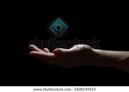 Computer chip hovers above hand on black background