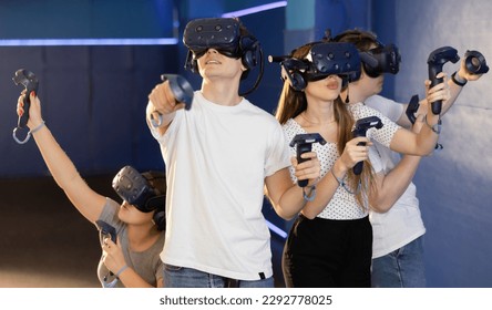 in computer club, group of four friends wearing virtual reality glasses and with joysticks are playing dynamic game with modern graphics. - Powered by Shutterstock