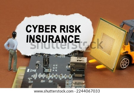 Computer concept. On the board with microcircuits lies a paper plate with the inscription - Cyber Risk Insurance. Nearby is a toy loader with a processor and a human figurine.