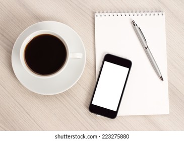 Computer desk with a cup of coffee, a notebook and pen