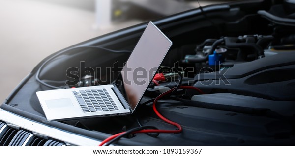 Computer\
diagnostics of the car in garage. Automotive mechanical technician\
using laptop computer programming and investing by car diagnostic\
software, car maintenance service\
concept.