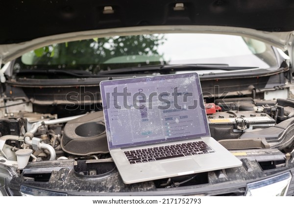 Computer\
diagnostics of the car in garage. Automotive mechanical technician\
using laptop computer programming and investing by car diagnostic\
software, car maintenance service\
concept