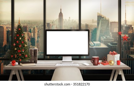 Computer Display On Table In Office With View On The City Skyscrapers Business Zone In Christmas Time. Christmas Tree, Gifts, Decorations In Background. 