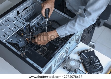 Computer engineer assembling high-performance PC at workshop desk.