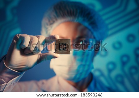 Computer engineer holding microchip for detailed analysis on the foreground 