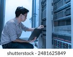 Computer engineer is setting up network in server room,Systems Maintenance Technician,Male engineer working in server room at modern data center