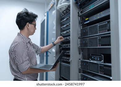 Computer engineer is setting up network in server room,Systems Maintenance Technician,Male engineer working in server room at modern data center - Powered by Shutterstock