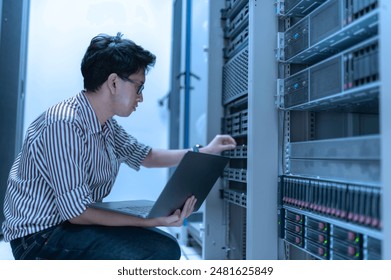 Computer engineer is setting up network in server room,Systems Maintenance Technician,Male engineer working in server room at modern data center - Powered by Shutterstock