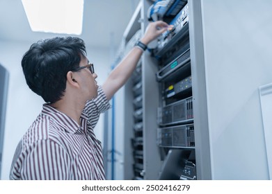 Computer engineer is setting up network in server room,Systems Maintenance Technician,Male engineer working in server room at modern data center