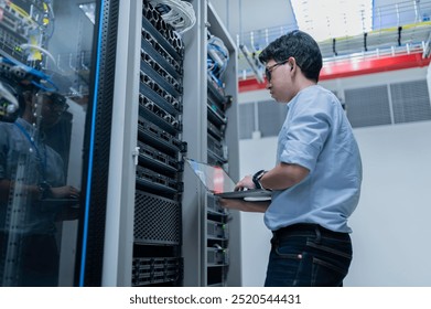 Computer engineer is setting up network in server room,Systems Maintenance Technician,Male engineer working in server room at modern data center - Powered by Shutterstock