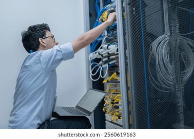 Computer engineer is setting up network in server room,Systems Maintenance Technician,Male engineer working in server room at modern data center
