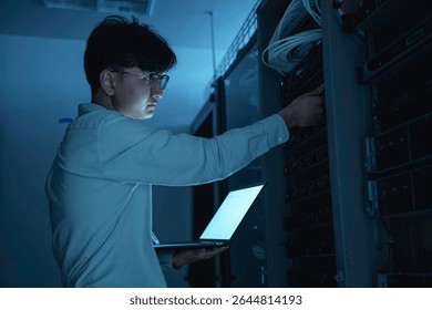 Computer engineer is setting up network in server room,Systems Maintenance Technician,Male engineer working in server room at modern data center