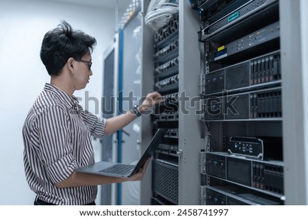 Computer engineer is setting up network in server room,Systems Maintenance Technician,Male engineer working in server room at modern data center
