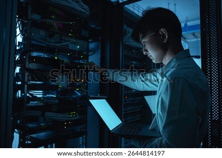 Computer engineer is setting up network in server room,Systems Maintenance Technician,Male engineer working in server room at modern data center