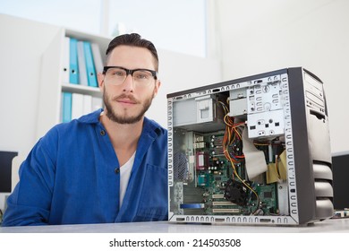 Computer engineer smiling at camera beside open console in his office