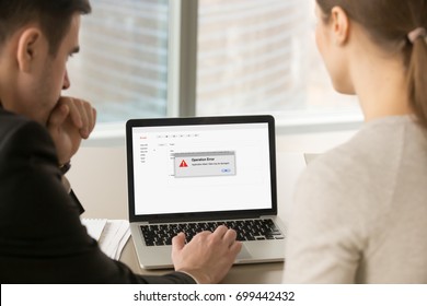 Computer error in office, businessman and businesswoman looking at laptop screen with reporting pop up message about application failure, pc crash, email app failed with data loss, close up back view