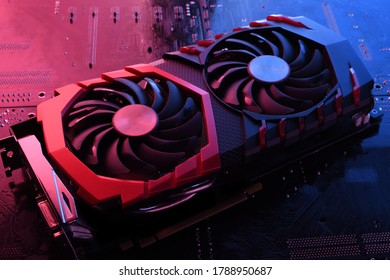 Computer game graphics card, videocard with two coolers on circuit board ,motherboard background. Close-up. With red-blue a lighting.