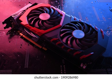 Computer game graphics card, videocard with two coolers on circuit board ,motherboard background. Close-up. With red-blue lighting.