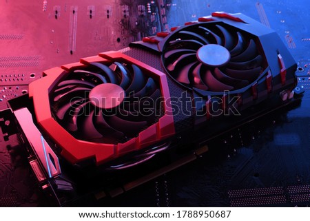 Computer game graphics card, videocard with two coolers on circuit board ,motherboard background. Close-up. With red-blue a lighting.