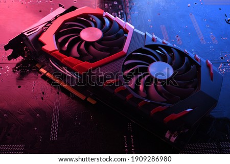Computer game graphics card, videocard with two coolers on circuit board ,motherboard background. Close-up. With red-blue lighting.