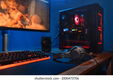 Computer gamer workplace with new game keyboard, mouse, headphones, modern pc with blur blue and red neon light. Powerful personal computer for e cyber sport gamer on the table at home. Close up