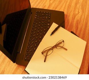 Computer, glasses, notebook and pen
