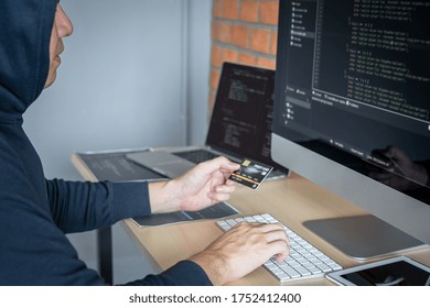 Computer hacker or cyber attack concept, Dangerous hooded hacker using multiple computers typing bad data into online system the access with a virus to infect steal information.