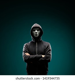 Computer Hacker In White Mask And Hoodie. Obscured Dark Face. Data Thief, Internet Fraud, Darknet And Cyber Security Concept.