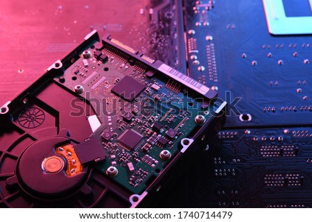 Computer Hard disk drives HDD , SSD on circuit board ,motherboard background. Close-up. With red-blue lighting