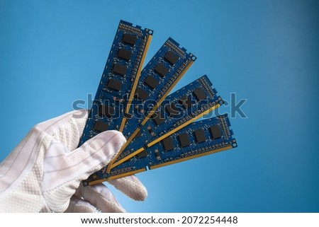Computer hardware DDR RAM board for PC in hand in glove on blue background