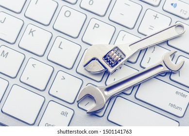 Computer hardware service and maintenance concept : Open-end wrench or spanner on a keyboard, depicts repairing / software setting and updating or changing to a newer version to improve performance