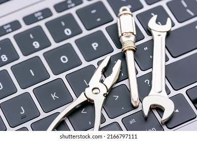 Computer hardware service and maintenance concept : Open-end wrench, a screwdriver, a needle-nose plier on a computer keyboard, depicts repairing, software updating or changing to a newer version.