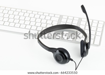 Computer headset with microphone on computer keyboard on white table - communication or helpcenter concept