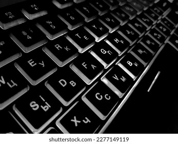 Computer keyboard black and white backlit close up.