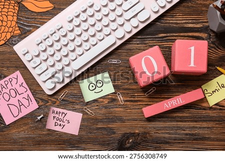 Computer keyboard, calendar and sticky notes on wooden background. April Fools Day prank